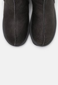 Zwarte instapschoenen met een soepel suède bovenwerk, een ronde neus en een contrasterende rubberen zool met textuur. Zichtbare stiksels langs de naden.