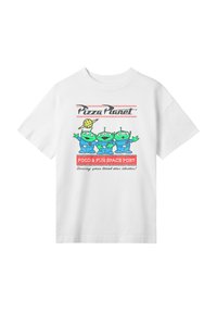 Bílý bavlněný tričko s barevným grafickým designem tří zelených mimozemšťanů v modrých oblecích, označené "Pizza Planet," s textem pod nimi.