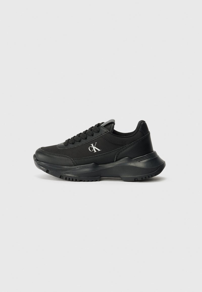 Des chaussures de sport noires en matériau synthétique lisse. Comprend des lacets, un col rembourré et un logo sur le côté. Semelle en caoutchouc épaisse pour un bon soutien.