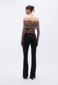 Top de cuadros marrón y beige con hombros descubiertos, combinado con jeans de mezclilla oscura de cintura alta y de pierna acampanada. Diseño sencillo, tela suave y silueta ajustada.