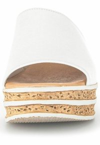 Tongs blanches avec une partie supérieure lisse, un design à bout ouvert et une semelle en liège texturée avec deux bandes horizontales blanches.