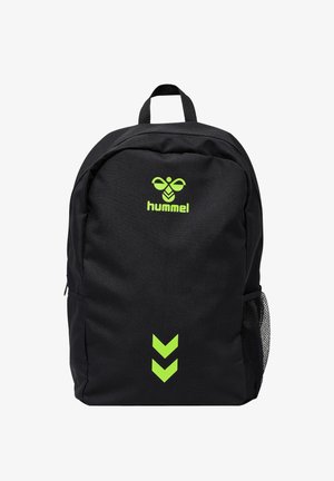 Zaino nero con logo Hummel verde neon e due chevron verso il basso, dotato di tasca laterale in rete e maniglia superiore per il trasporto.