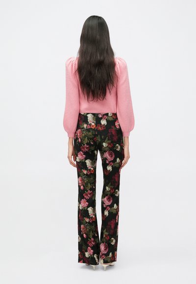 Ružový sveter s textúrou a nafúknutými rukávmi, skombinovaný s čiernymi kvetinovými nohavicami s viacfarebnými ružami a zelenými detailmi. Vysoký pás, zvonový strih.