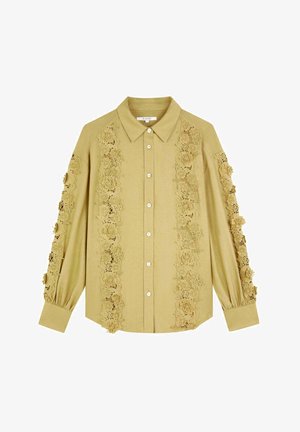 Langärmliges beiges Hemd mit Knopfleiste und komplizierten floralen Spitzenverzierungen an den Ärmeln und Vorderseiten.