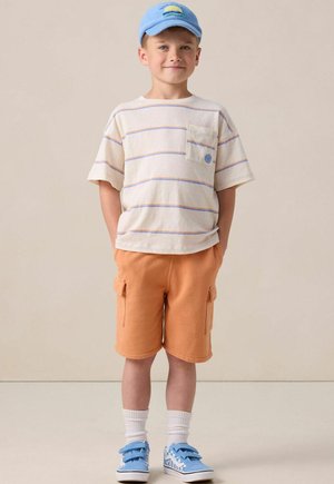 Kurzärmliges gestreiftes T-Shirt mit Tasche, orange Cargo-Shorts, blauer Hut, weiße Socken, blaue Klettschuhe mit Muster.