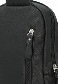 Bolso de cuero negro con superficie texturizada, cremalleras visibles, una pequeña correa de acento y herrajes en plata. Enfoque en el diseño elegante y la funcionalidad.