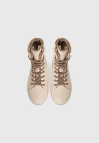 Sneaker alte beige con lacci marroni e rivestimento in pelliccia, viste dall'alto su uno sfondo bianco semplice.