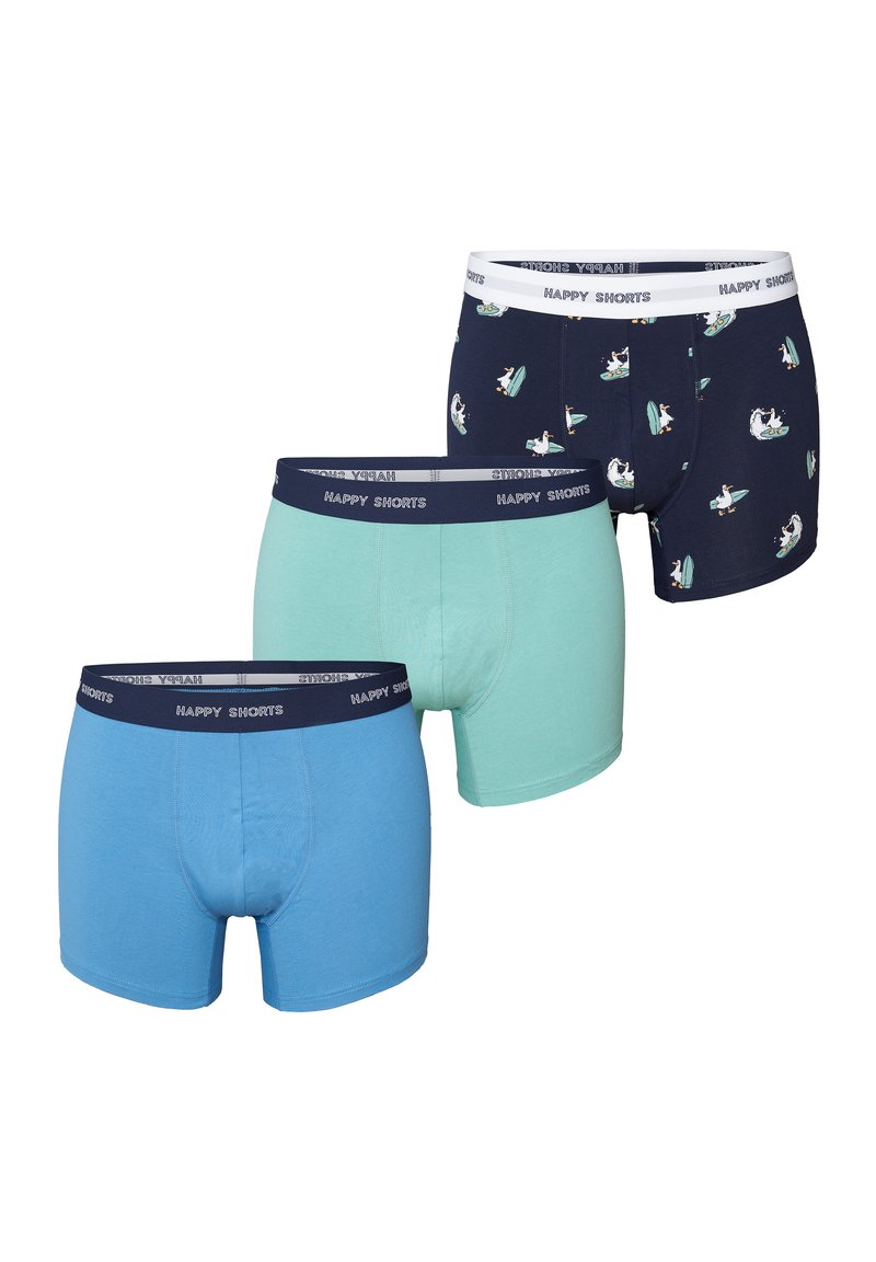 Drie paar herenboxershorts: lichtblauw, mintgroen en marineblauw met een surferpatroon. Allemaal voorzien van elastische taillebanden met de tekst "HAPPY SHORTS".