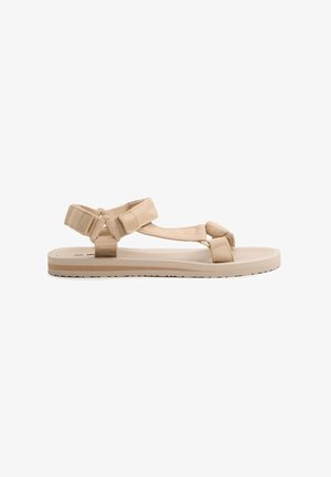 Sandalias planas beige con suela de goma texturizada, con tiras de tela ajustables y un diseño sencillo. Ligeras y prácticas para uso al aire libre.