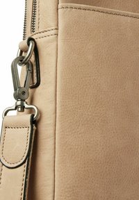 Beigeledertasche mit strukturiertem Finish, silbernem Zubehör und einem abnehmbaren Riemen mit einer genähten Lederakzent.
