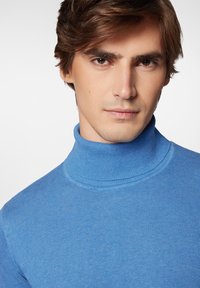 Niebieski sweter z golfem, wykonany z miękkiego materiału; ma dopasowany krój, wysoki kołnierz i gładką teksturę. Brak wzorów lub akcentów.