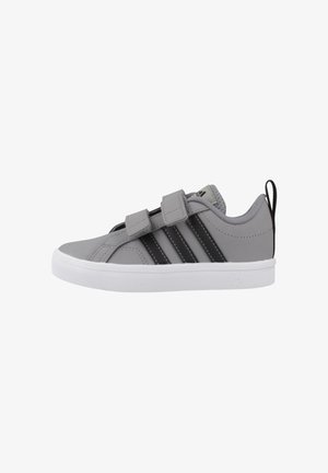 Zapatillas sintéticas grises con rayas negras, con suela de goma blanca, dos tiras ajustables de velcro y una lengüeta en el talón.