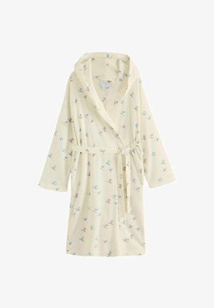 Krēmkrāsas kapuces tipa halāts ar mazām krāsainām slēpotāja raksta detaļām un jostas siksnu, kas sasieta viduklī.