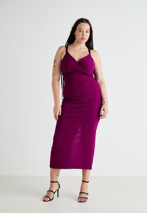 Fitted purple ribbed dress with a twisted front detail, thin straps, and a calf-length hem, paired with black strappy high heels.