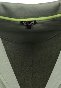 Detalle en primer plano de un escote de tela de punto verde con una etiqueta de la marca "KEY LARGO" en negro y una etiqueta de tamaño "S" cosida en el interior.