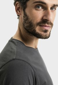 Czarnoszary bawełniany t-shirt z okrągłym dekoltem, o gładkiej fakturze i minimalistycznym designie, podkreślony kontrastującymi szwami.