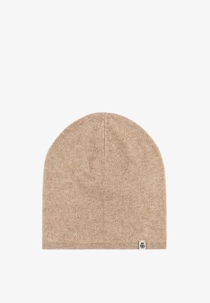Beige knitted beanie hat with a smooth texture, tapered top, and a small logo patch on the bottom edge.
