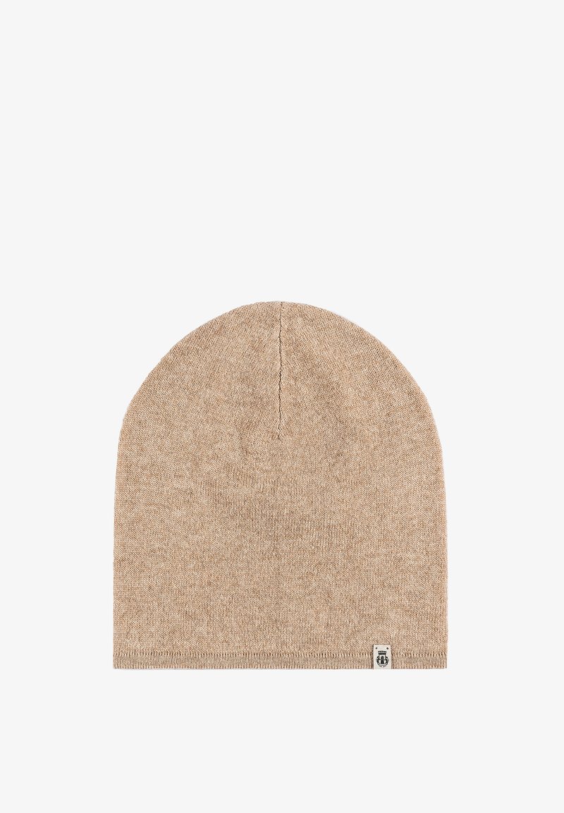 Beige knitted beanie hat with a smooth texture, tapered top, and a small logo patch on the bottom edge.