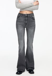 Jeans gris acampanados de mezclilla con un ligero desgastado, que presentan bolsillos frontales y una cintura ajustada para un aspecto estructurado.