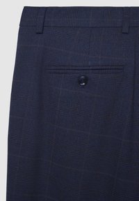 Marineblaue Karohosen mit knöpfbarer Gesäßtasche und Gürtelschlaufen, die die Stofftextur und Musterdetails zeigen.