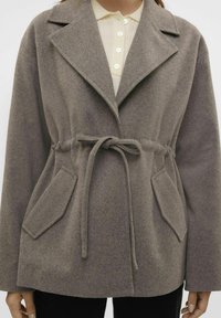 Grijze wollen mantelmix met een brede kraag, getailleerde taille en twee zakken aan de voorkant. Heeft een gestructureerde stof en een ceintuur om zelf te knopen.