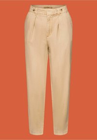 Pantalon beige taille haute fuselé avec plis sur le devant, poches latérales et détails de boutons à la taille sur fond orange.