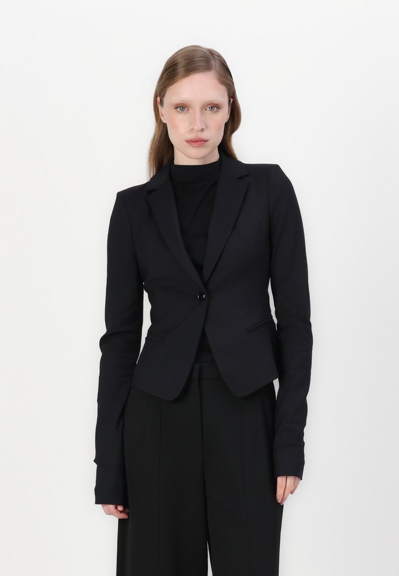 Černý přizpůsobený blazer s jednobotonovým zapínáním, klopovými límci a dlouhými rukávy. Vyrobený z hladké látky, s přizpůsobenými liniemi a kapsami.