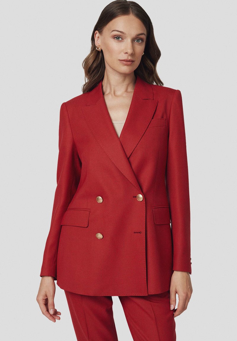 Czerwona marynarka dwurzędowa z teksturowanej tkaniny, z złotymi guzikami, klapami oraz bocznymi kieszeniami. Dopasowany krój, długie rękawy.