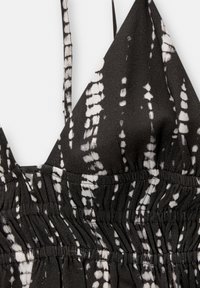 Haut à nouer noir et blanc avec bande élastique froncée à la taille et bretelles étroites.