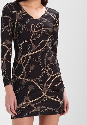 Zwarte jurk met lange mouwen en V-hals, voorzien van een patroon van gouden kettingen en kralen, aansluitend op het lichaam, gemaakt van een gladde, rekbare stof.