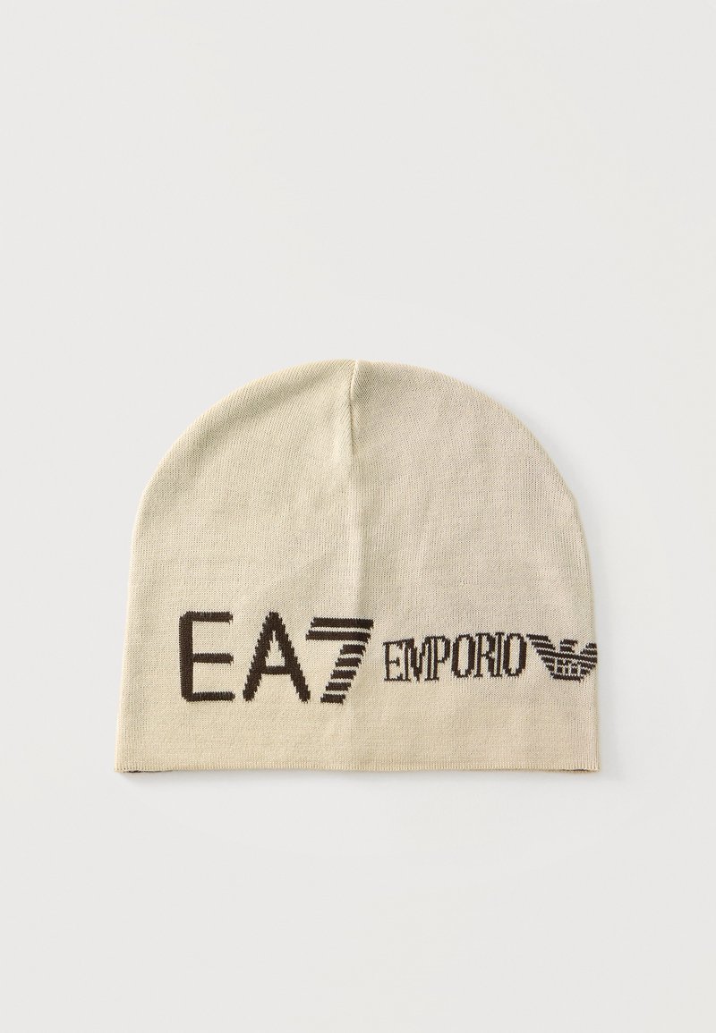 Μπεζ πλεκτό σκουφί με μαύρο λογότυπο "EA7 Emporio Armani" και έμβλημα αετού στο μπροστινό μέρος σε ανοιχτό φόντο.