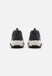 Schwarze und lila Sportschuhe mit einem Obermaterial aus Netzgewebe, strukturierter Oberfläche und multidirektionalen Gummisohlen, ausgestattet mit Zuglaschen und verstärktem Absatz.