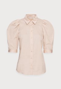 Ljusbeige button-up blus med puffade trekvartslånga ärmar och en spetsig krage mot en vit bakgrund.