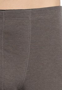 Grijze rekstof met een gladde textuur. Heeft een brede tailleband en platte naden, ontworpen voor comfort en veelzijdigheid.