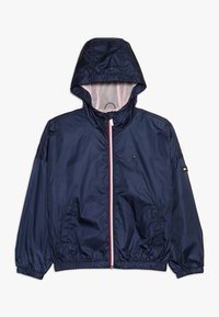 Giacca leggera blu navy con cappuccio, polsini elasticizzati e zip frontale. Presenta dettagli rossi e bianchi, fodera in rete e tasche laterali.