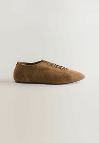 Scarpa in suede marrone con lacci, punta affusolata, profilo basso e minima cucitura. Texture liscia con suola in gomma nera.