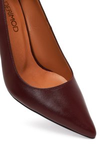 Talons hauts en cuir bordeaux avec un bout pointu, texture lisse et design épuré. L'intérieur comporte une semelle en tan. Détails minimalistes.