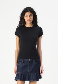 Zwarte t-shirt met korte mouwen en een ronde hals, gecombineerd met een donkere spijkerrok met een gerimpelde onderrand en voorzakken.