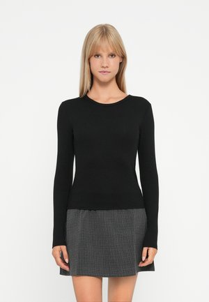 Black ribbed long-sleeve top with a round neckline, paired with a short black and white checked skirt, featuring a flared design.