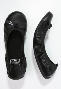 Svarta läderballetskor med rund tå, elastiska kanter och en dekorativ rosett. Har en vadderad sula och flexibel sula.