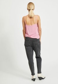 Růžový top na ramínka s tenkými popruhy, kombinovaný s tmavě šedými vysokými zúženými džínami. Obsahuje boční kapsy a má mírně volný střih.