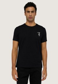 Czarna bawełniana koszulka z krótkim rękawem i okrągłym dekoltem, z małym haftowanym wzorem po lewej stronie na klatce piersiowej. Gładka faktura, luźny krój.