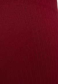 Close-up van dieprode stof met fijne horizontale en verticale geribbelde patronen.