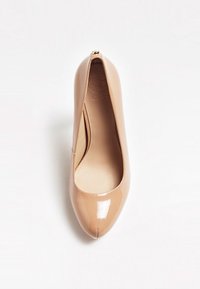 Chaussure à talon haut pointue en cuir verni couleur nude avec une décoration dorée sur la languette arrière du talon, sur fond blanc.