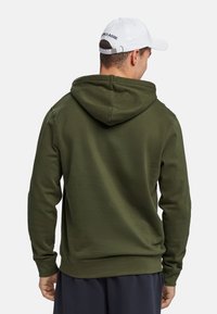 Olivegrøn hættebluse med snoretræk i huen og ribbede manchetter. Stofudseendet er blødt, og designet har en ren, klassisk silhuet.