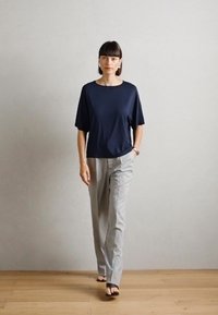 Top blu navy a maniche corte abbinato a pantaloni dritti grigio chiaro. Tessuto morbido con una vestibilità rilassata, design semplice e decorazioni minime.