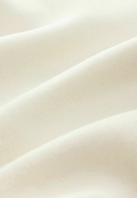 Weißer Stoff mit einer glatten, leicht strukturierten Oberfläche, die sanfte Wellen und subtile Farbvariationen im Material aufweist.