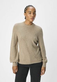 Beżowy sweter z dzianiny z okrągłym dekoltem, z ukośnym prążkowaniem i małymi wycięciami po jednej stronie. Długie, lekko bufiaste rękawy.