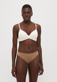 Witte, licht gewatteerde bh met verstelbare bandjes, gecombineerd met tan lage bikini-broekjes. Gladde textuur, naadloos ontwerp.