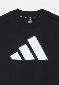 Čierna mikina vyrobená z bavlny, s veľkým bielym logom Adidas na prednej strane. Hladký vzhľad, dizajn s okrúhlym výstrihom a rebrovaným golierom.